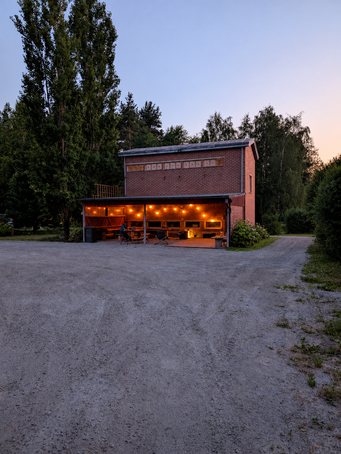 Tiilirakennus ja sen katettu terassi pihalta kuvattuna